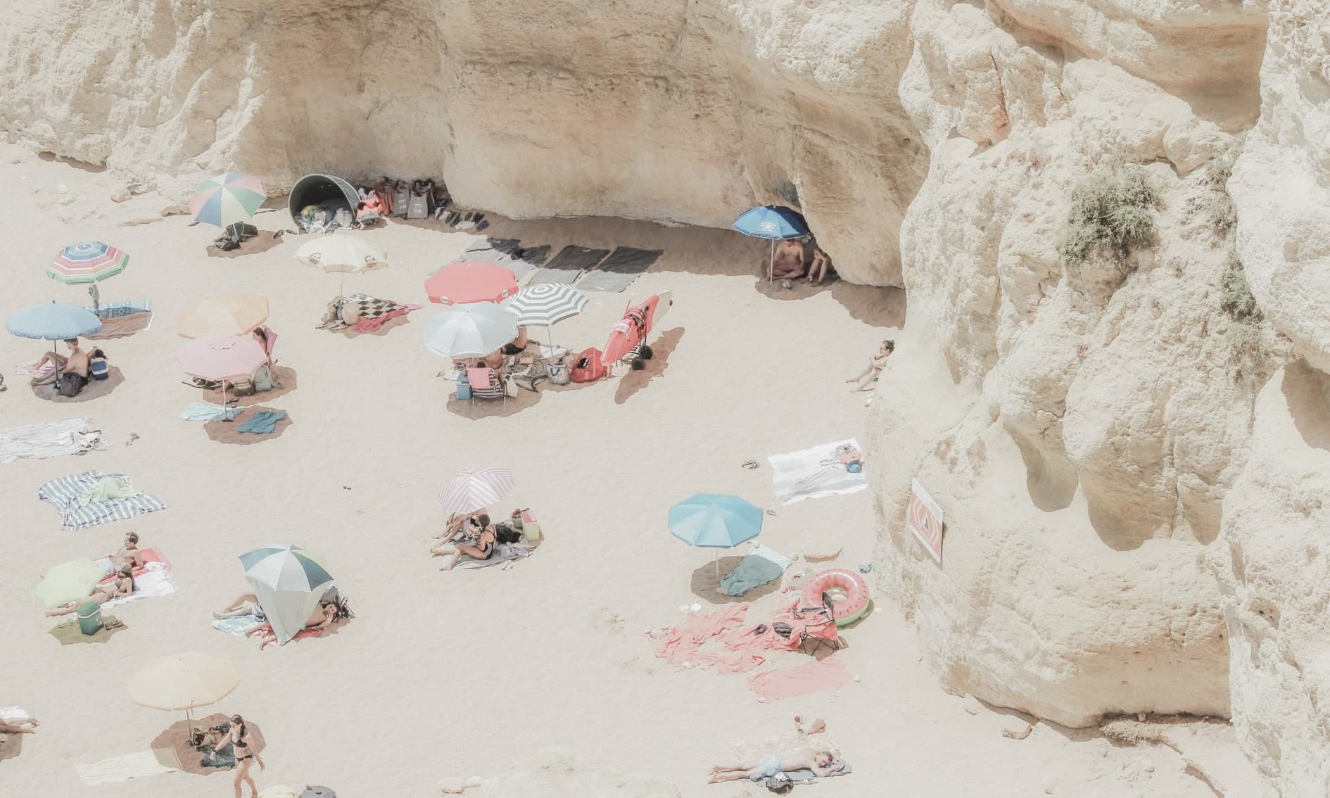 Cenital de playa con quitasoles de colores y bañistas entre rocas/acantilados claros. Agua #P8, fotografía de Cristian Letelier, edición limitada