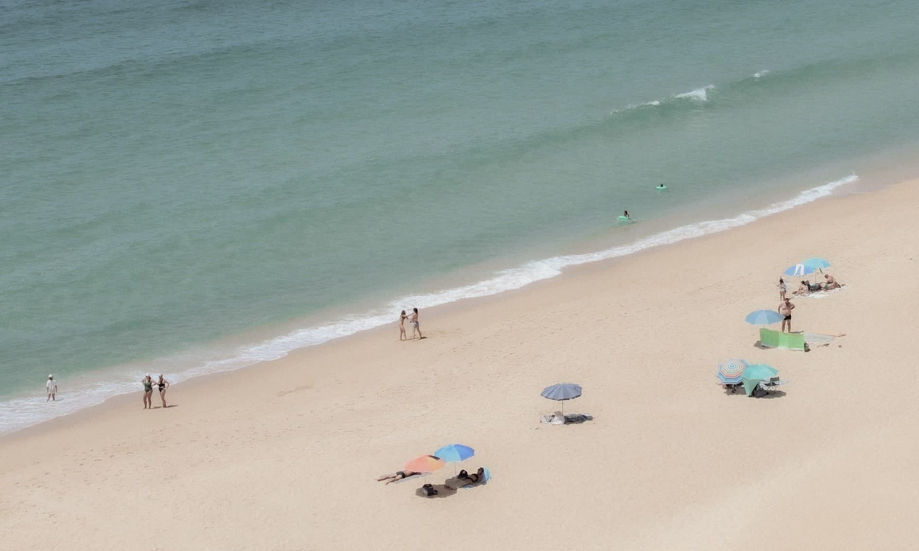 Playa vista desde alto: mar verde turquesa, orilla con pocas personas y quitasoles de colores. Agua #P15, fotografía de Cristian Letelier, edición limitada