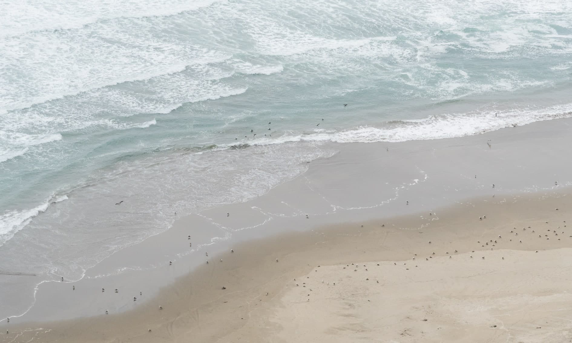 Vista alta de playa: olas espumosas grises, orilla ancha con personas diminutas. Agua #P19, fotografía de Cristian Letelier, edición limitada