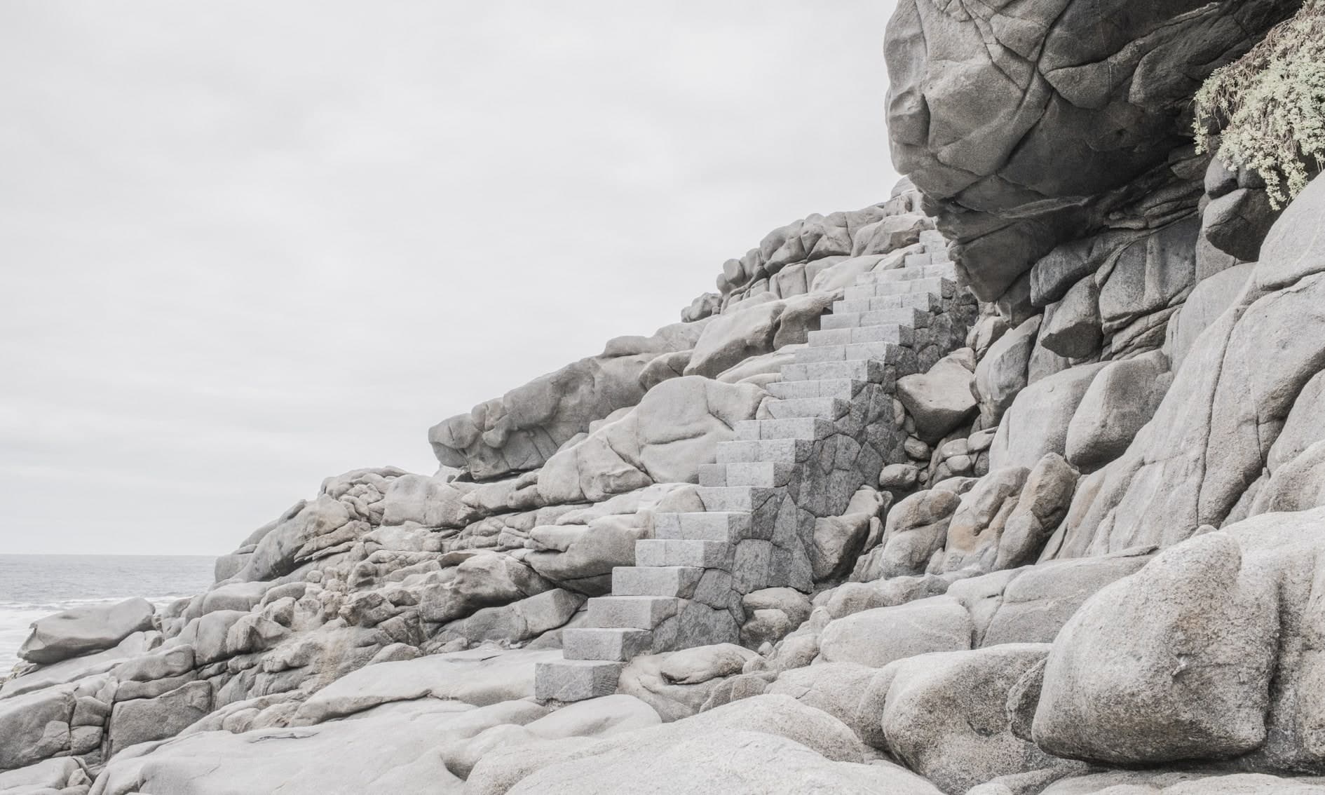 Escalera de piedra tallada subiendo entre rocas graníticas claras, mar a la izquierda. Agua #P21, fotografía de Cristian Letelier, edición limitada