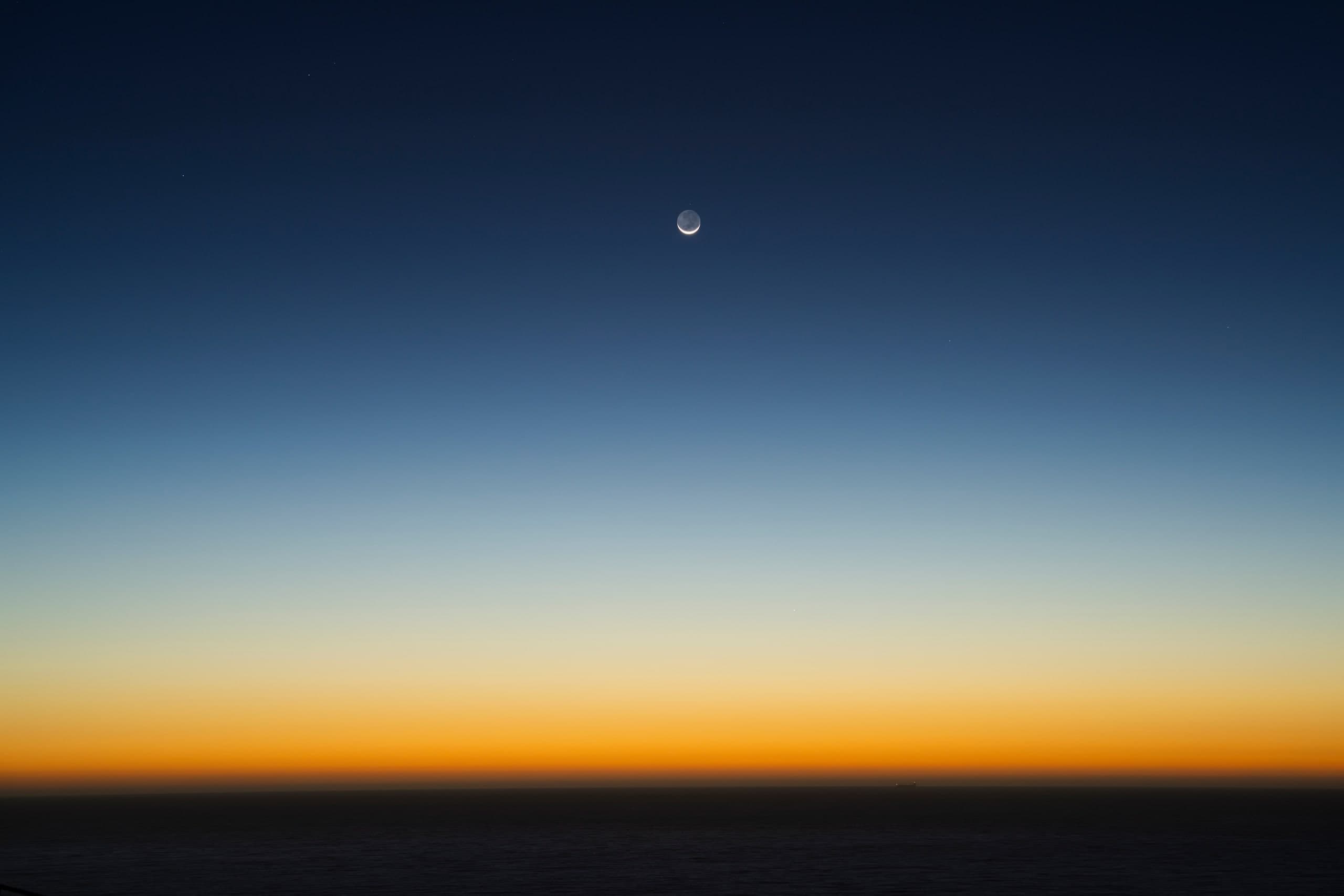 Atardecer sobre el mar: degradado del azul profundo al naranja, con la luna creciente. Agua #P51, fotografía de Cristian Letelier, edición limitada