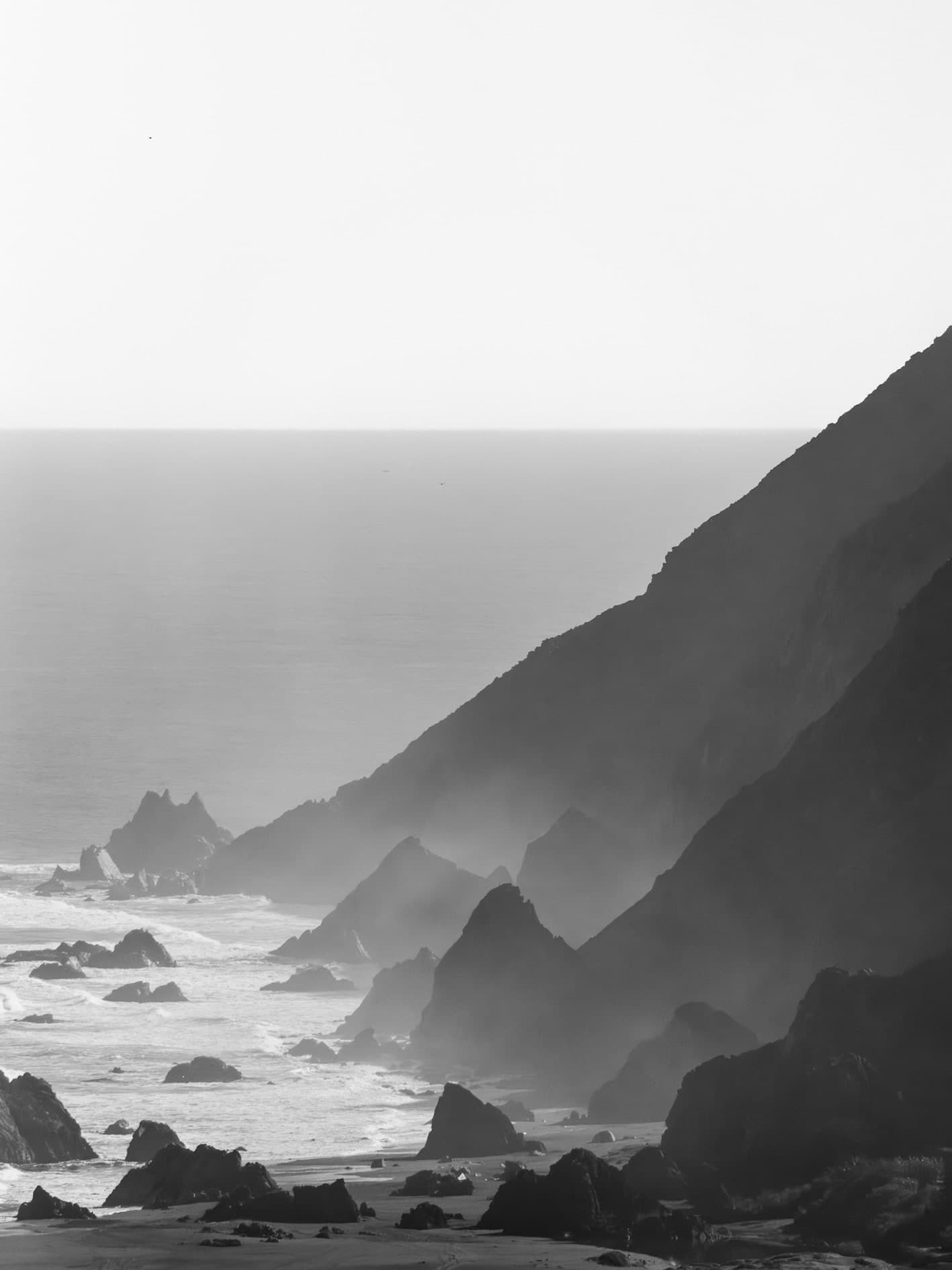 Vertical B/N: acantilados y cerros en capas con bruma, roqueríos y mar. Agua #P34, fotografía de Cristian Letelier, edición limitada