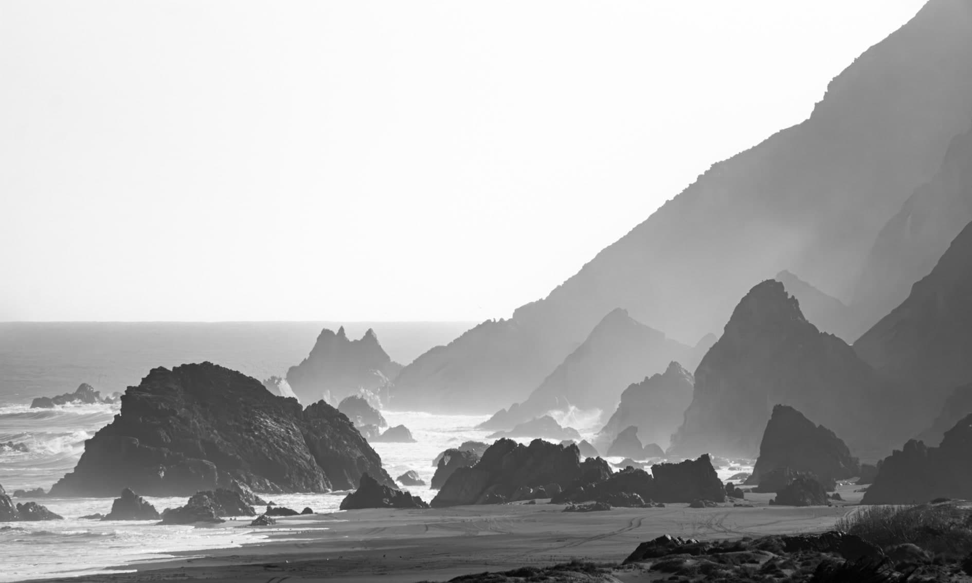 B/N horizontal: cerros y acantilados en capas con bruma, roqueríos y olas rompiendo. Agua #P37, fotografía de Cristian Letelier, edición limitada