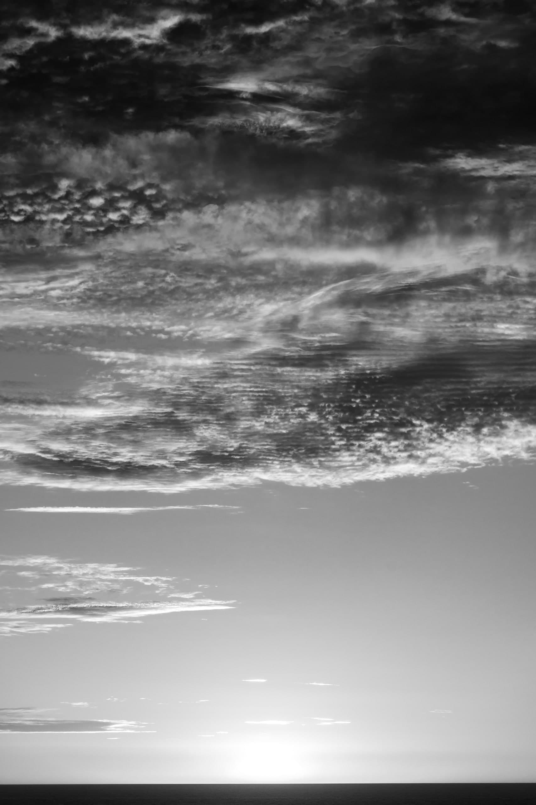 Cielo de nubes grises y blancas sobre una franja de mar, vertical, en blanco y negro. Agua #P46, fotografía de Cristian Letelier, edición limitada