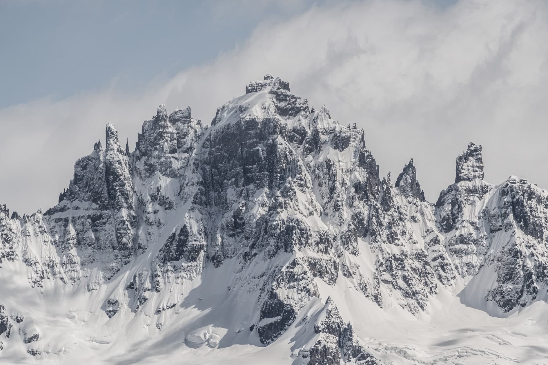 Macizo de agujas rocosas cubiertas de nieve, cumbres afiladas, cielo nuboso claro. Aire #C1, fotografía de Cristian Letelier, edición limitada