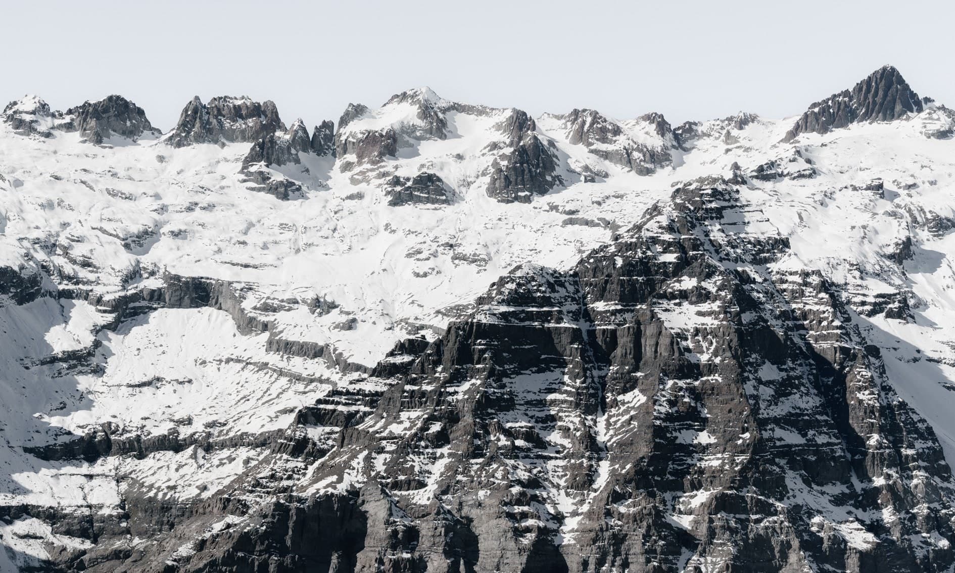 Pared rocosa oscura veteada de nieve con cumbres afiladas arriba. Aire #C16, fotografía de Cristian Letelier, edición limitada