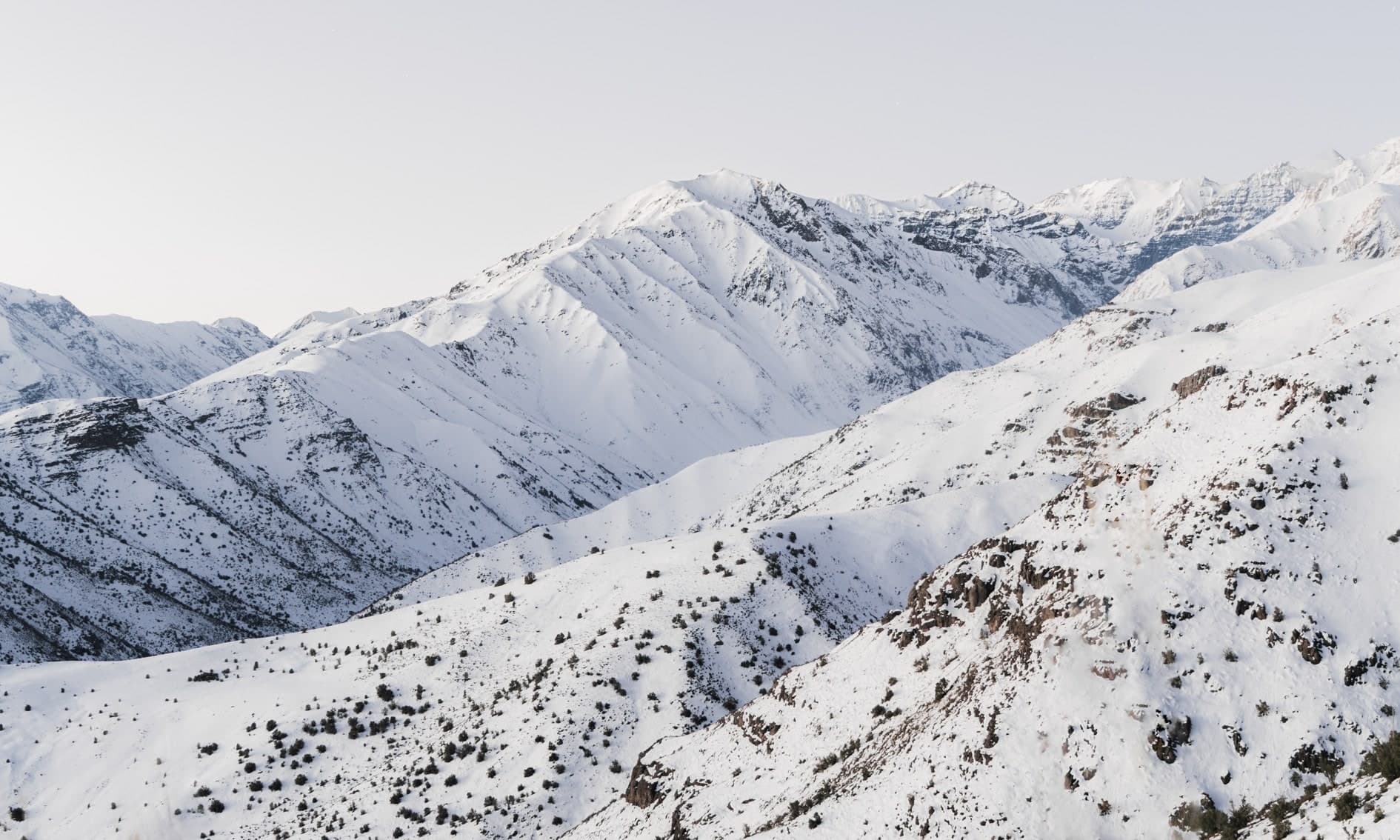 Laderas nevadas con arbustos oscuros dispersos, cordón al fondo, luz suave rosada. Aire #C3, fotografía de Cristian Letelier, edición limitada