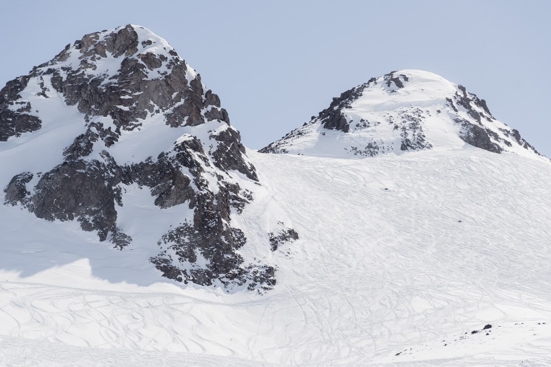 Dos cumbres: una rocosa oscura a la izquierda y una nevada redondeada a la derecha, nieve con huellas. Aire #C8, fotografía de Cristian Letelier, edición limitada