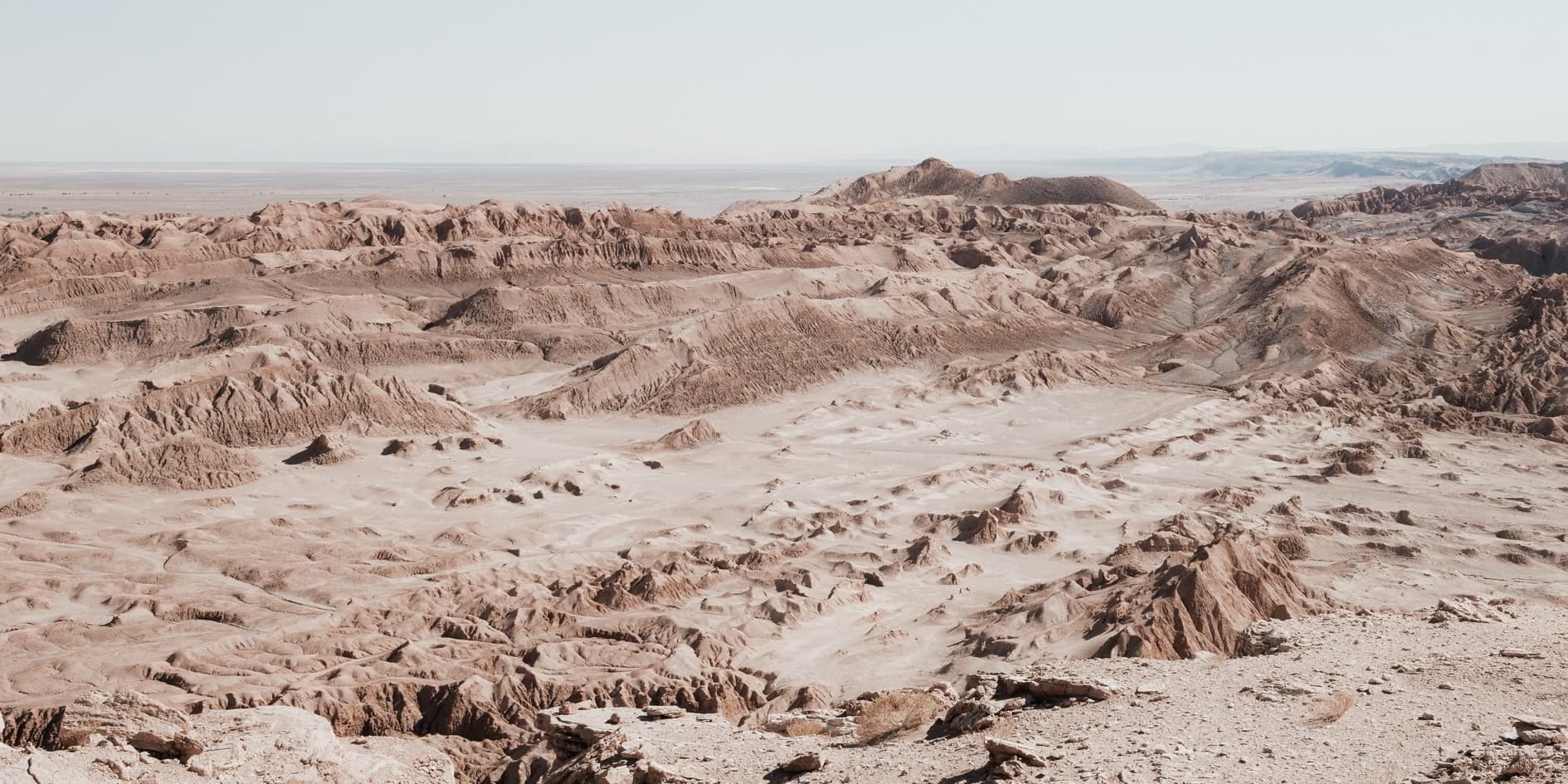 Vista elevada de badlands erosionados color ocre-rosado tipo Valle de la Luna, sin agua, cielo pálido. Fuego #D8, fotografía de Cristian Letelier, edición limitada
