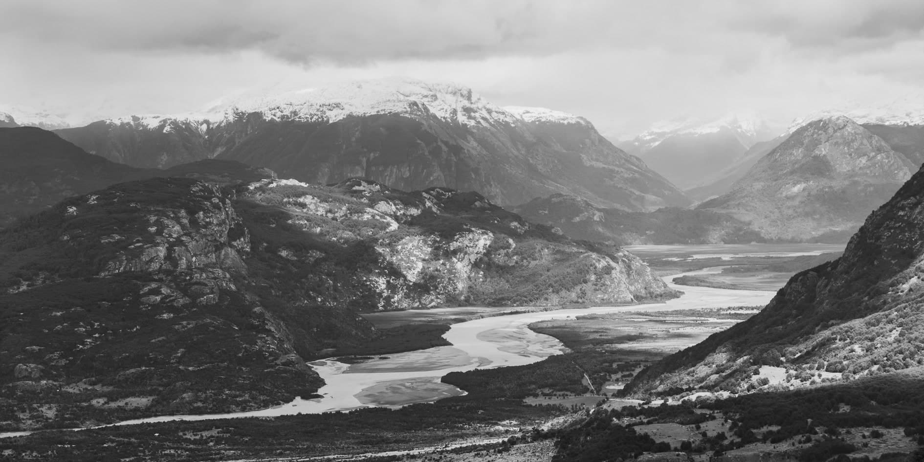 Vista elevada de río serpenteante entre montañas nevadas; blanco y negro. Tierra #S18, fotografía de Cristian Letelier, edición limitada