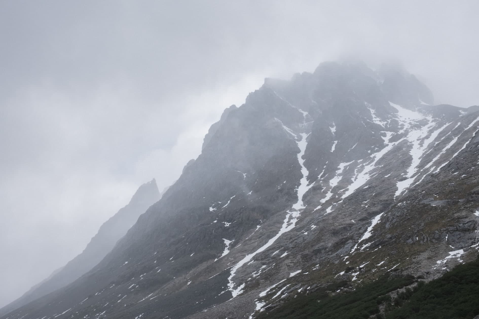 Montaña rocosa con manchas de nieve entre niebla densa; color desaturado. Tierra #S21, fotografía de Cristian Letelier, edición limitada