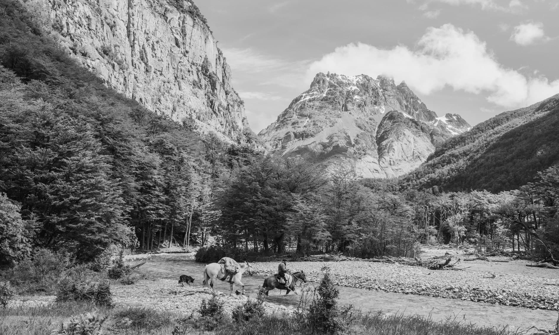 Jinete con caballos y perro cruzando río en valle con montañas; blanco y negro. Tierra #S23, fotografía de Cristian Letelier, edición limitada