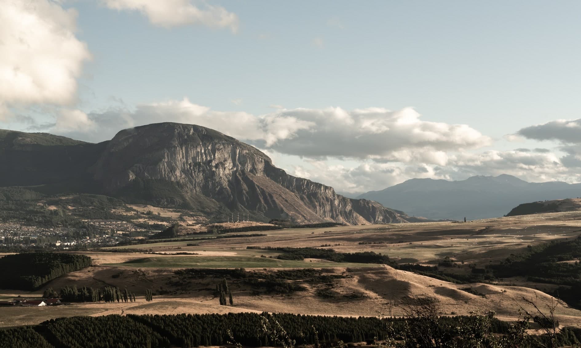 Cerro rocoso sobre valle con pueblo, campos y nubes; color cálido. Tierra #S25, fotografía de Cristian Letelier, edición limitada