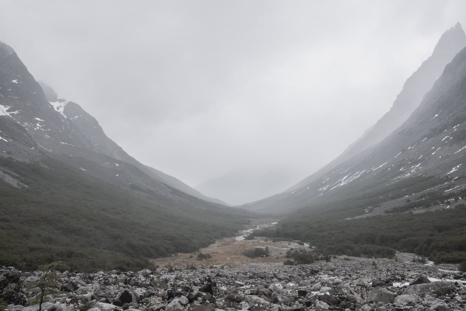 Valle en U con río, niebla y campo de rocas en primer plano; color desaturado. Tierra #S27, fotografía de Cristian Letelier, edición limitada