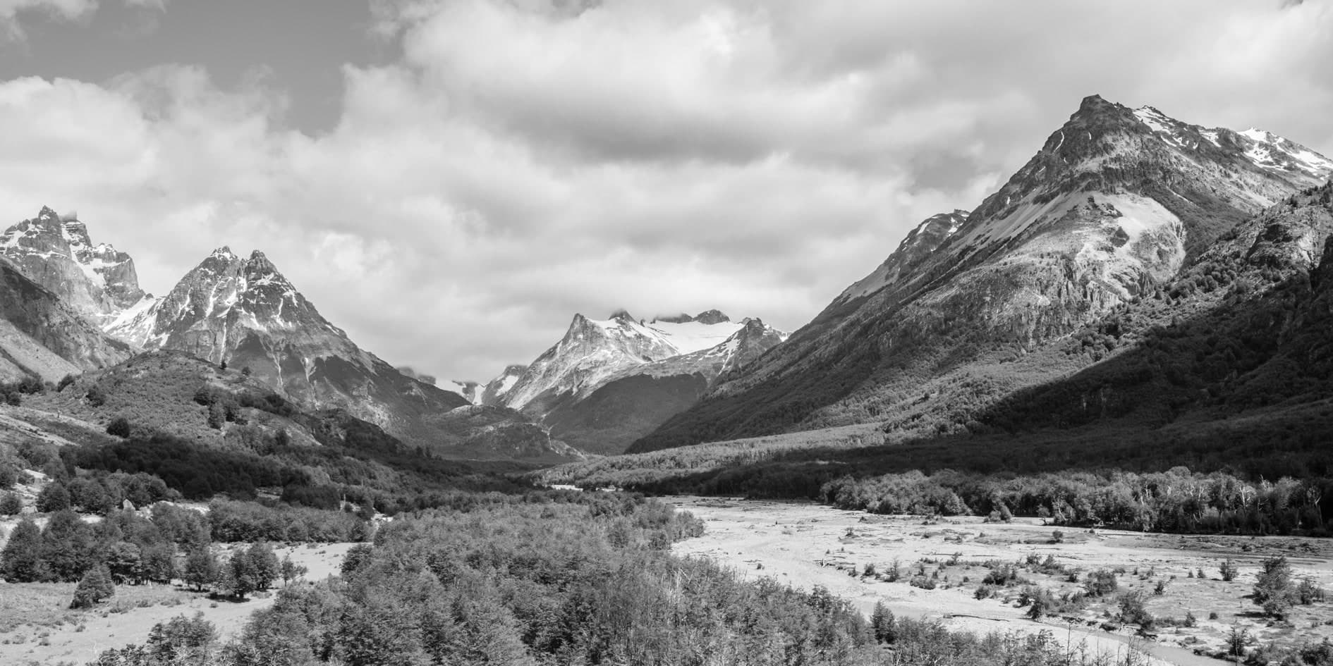 Valle amplio con montañas nevadas, río y bosque, cielo con nubes; blanco y negro. Tierra #S5, fotografía de Cristian Letelier, edición limitada